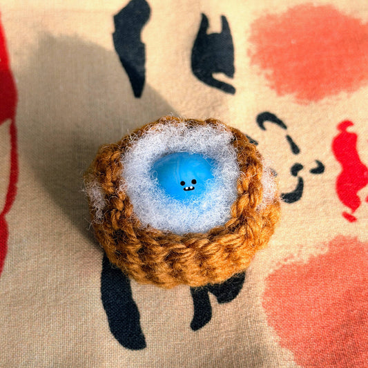 Bonino in a blue swirl color. Nestled in a crochet basket. Front facing.
