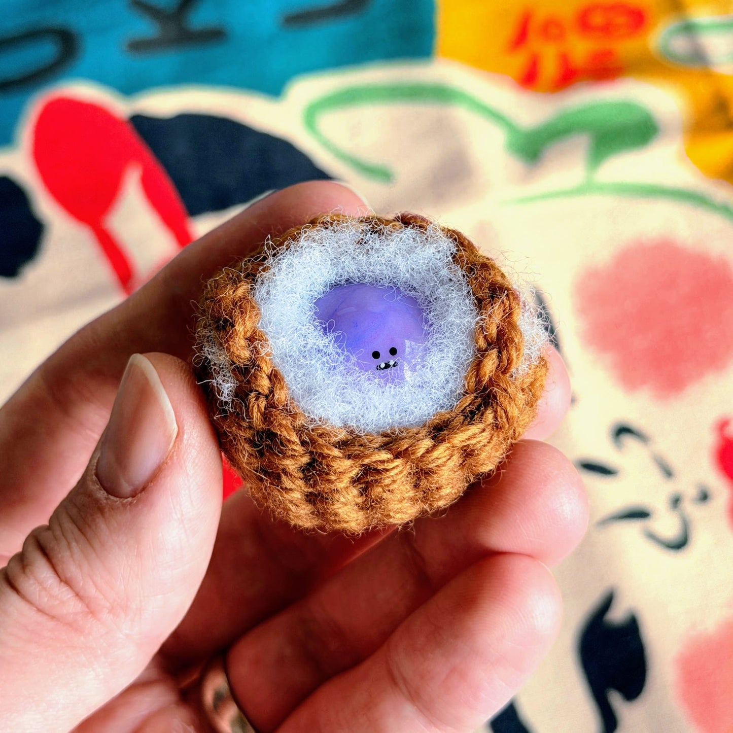 Bonino in a purple swirl color being held while nestled in a crochet basket.