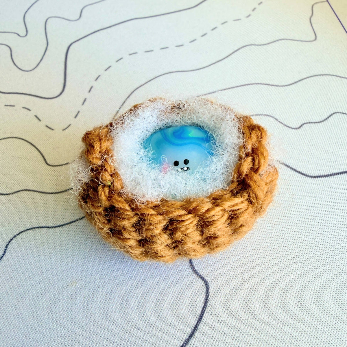A handmade special edition Bonino - 90s water elemental swirl design - sitting in handmade crochet basket.